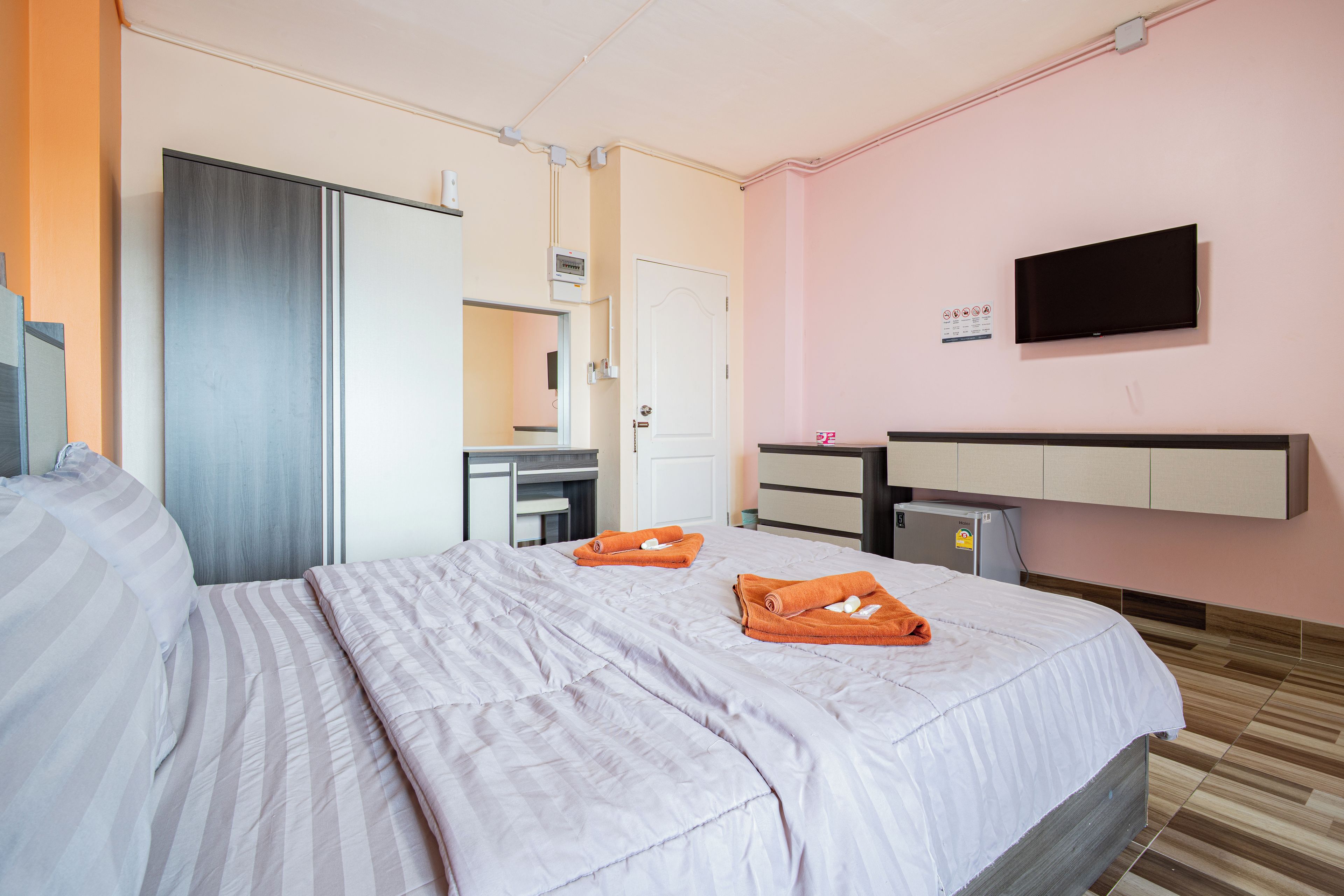 A hotel room with a bed, a desk, a television, and a minibar.