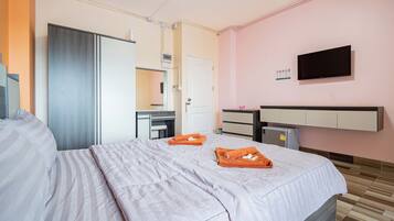 A hotel room with a bed, a desk, a television, and a minibar.