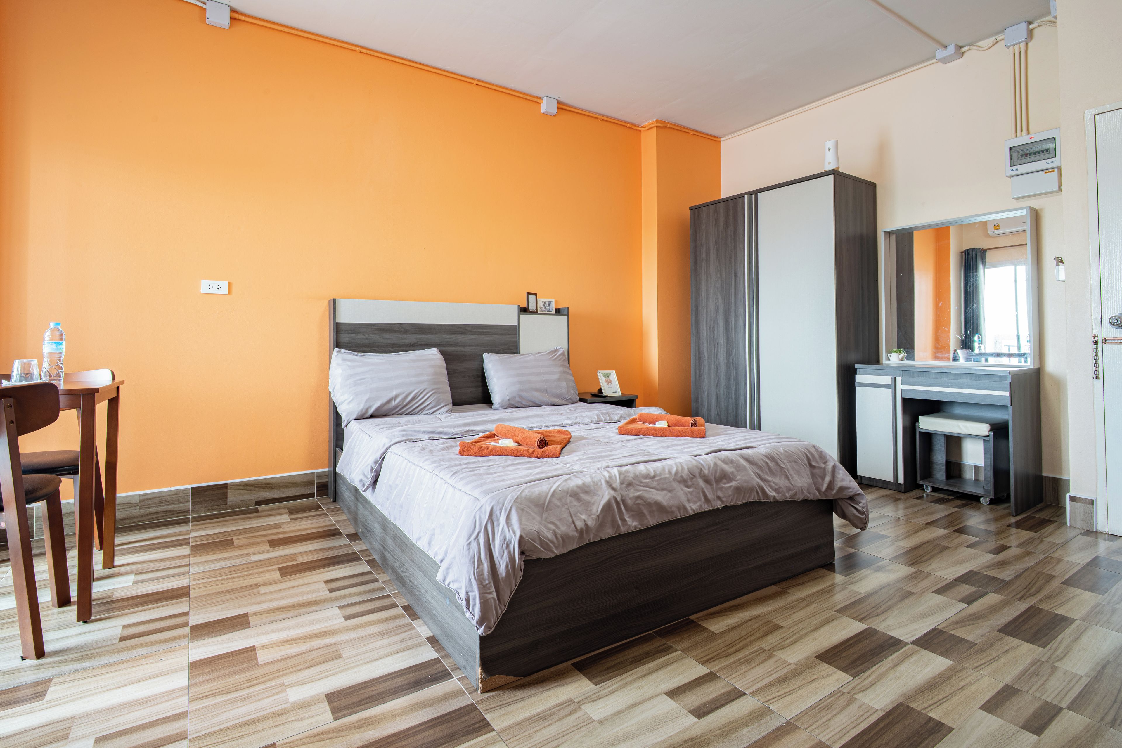 A hotel room with a bed, a desk, a chair, and a wardrobe.