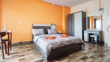 A hotel room with a bed, a desk, a chair, and a wardrobe.