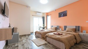 A hotel room with two beds, a TV, a desk, and a window. - The Wish Hotel (Chachoengsao)