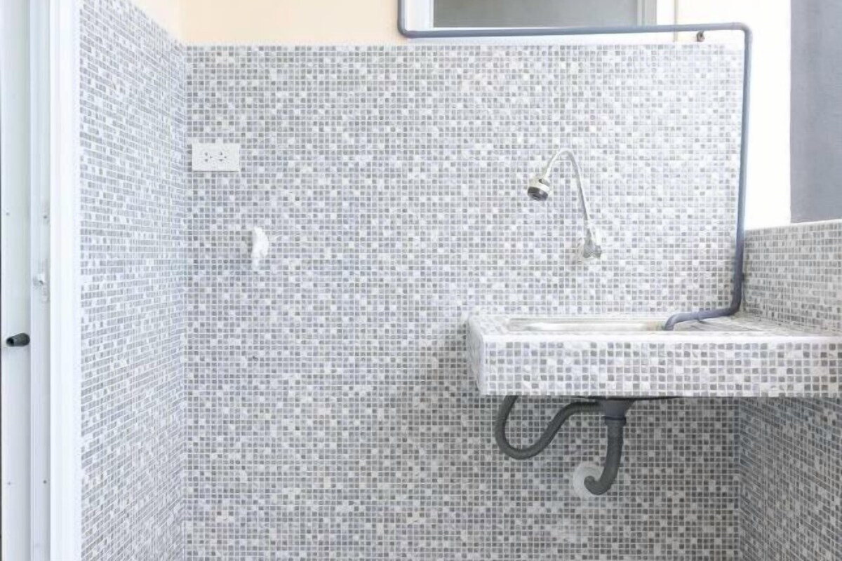 A bathroom with a tiled shower enclosure and a sink with a towel rack.