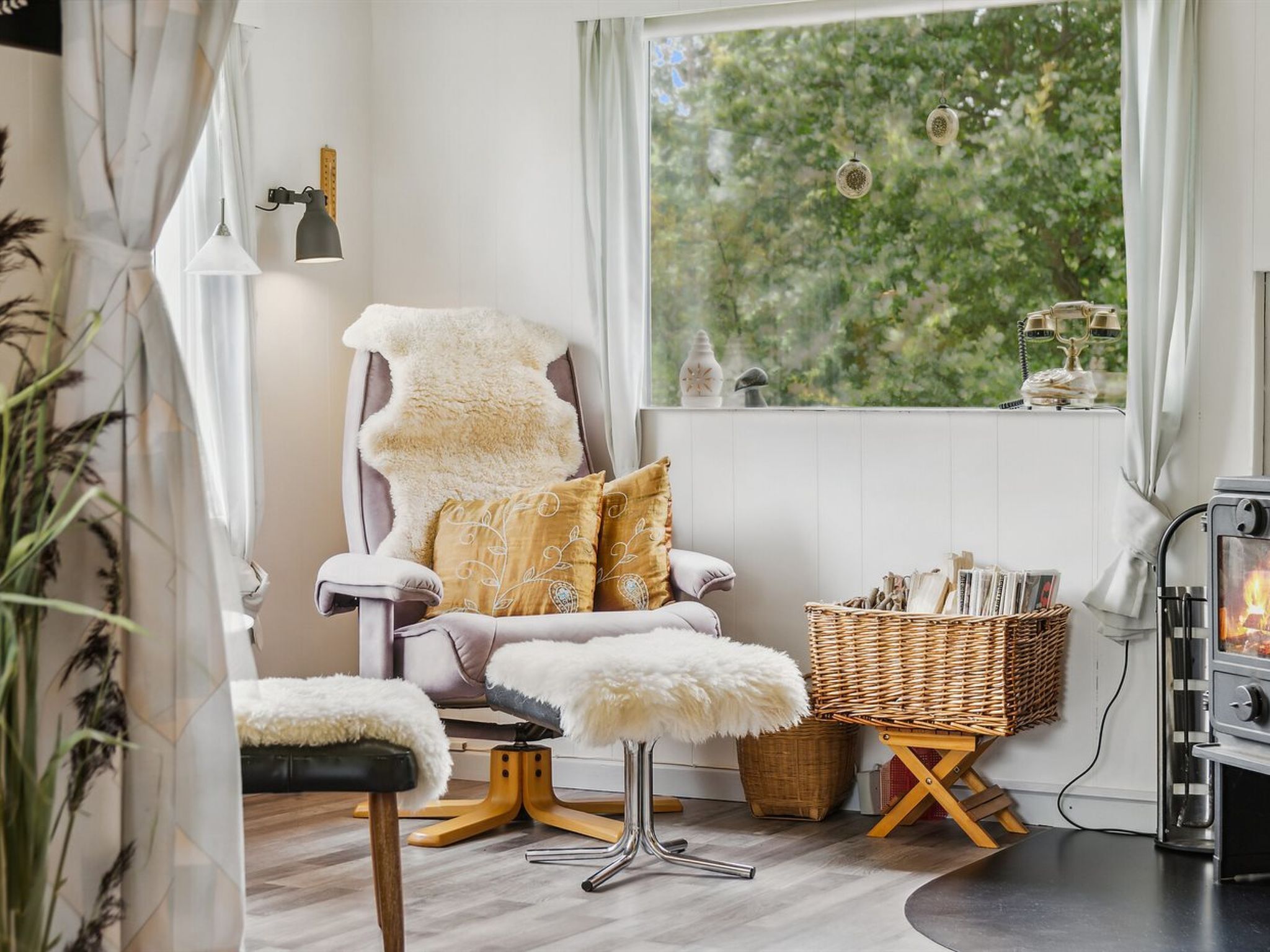 Une pièce chaleureuse avec un fauteuil moelleux, un petit tabouret, un panier en osier et un poêle à bois.