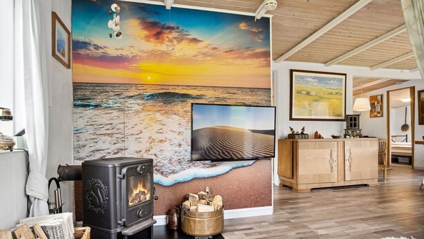 Un soggiorno accogliente con camino, un'ampia parete decorata con un murale raffigurante una spiaggia e un mobiletto in legno.