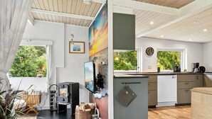 Una cucina moderna con stufa a legna, zona pranzo e vista sul verde.