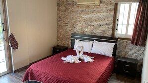 A hotel room with a brick-patterned wall, a bed with a red quilt, and a heart-shaped towel decoration. - Less than five minutes from the beach, restaurants, supermarkets, bakery's (Paralimni)