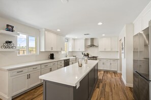 A modern kitchen with white cabinetry, a central island, and a stainless steel refrigerator.