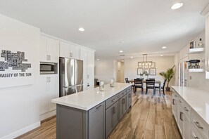 A modern kitchen with white cabinetry, a stainless steel refrigerator, and a central island. - 4BR + Casita w/ Pool + Outdoor Big Screen (Scottsdale)