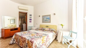 A bedroom with a bed, a dresser, a chair, a small table, and a painting on the wall. - 055 Villa Retiro (Denia)