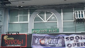 A building with a sign for 'Hotel Rivoli - Cafe & Restaurant' and another sign for 'El Coco Bldg.' with a 'Soon to Open' banner. - Rivoli Hotel (San Pablo)
