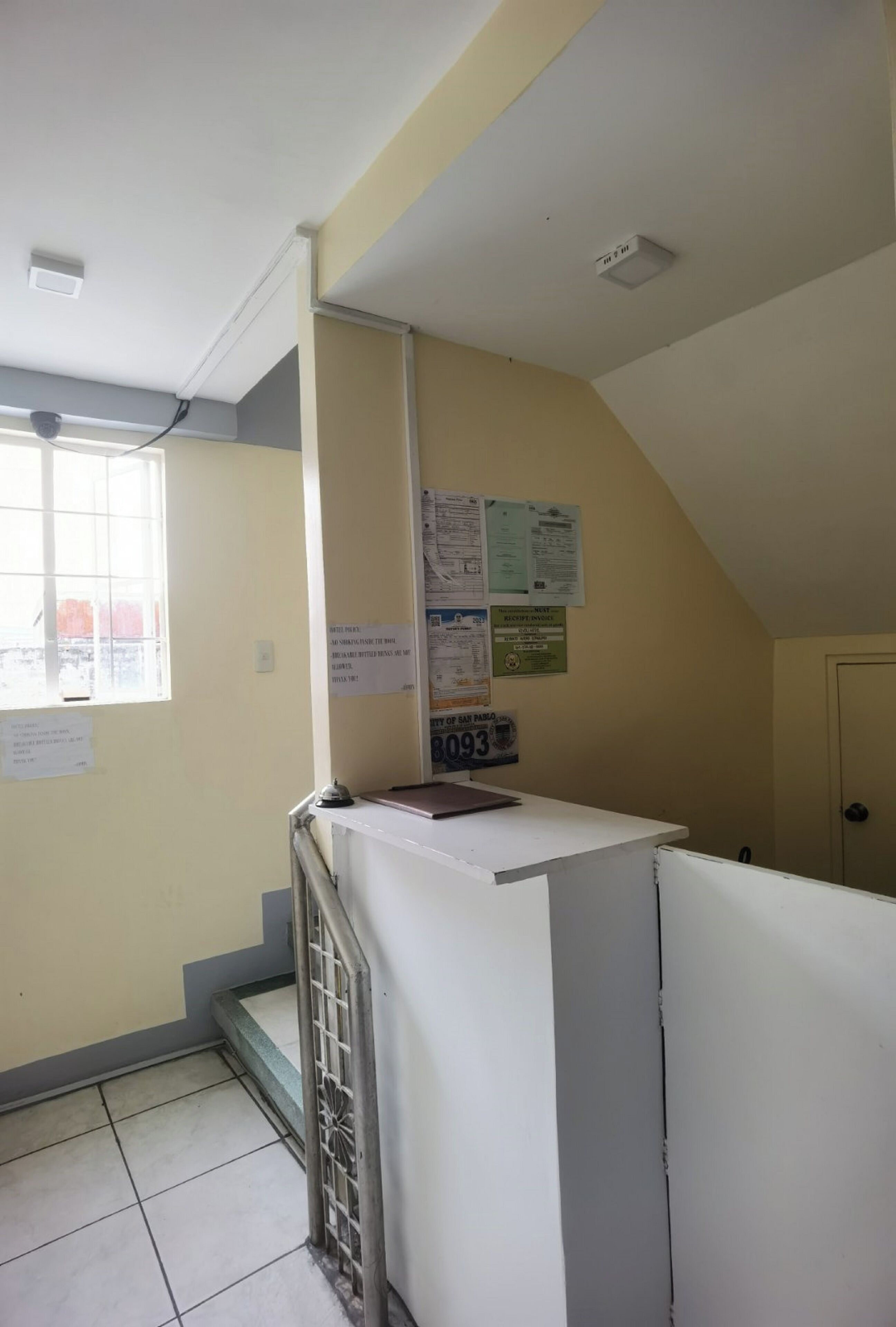 A hotel room with a desk, a window, and a door.