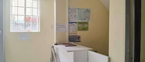 A narrow hallway with a window, a bulletin board, and a door.