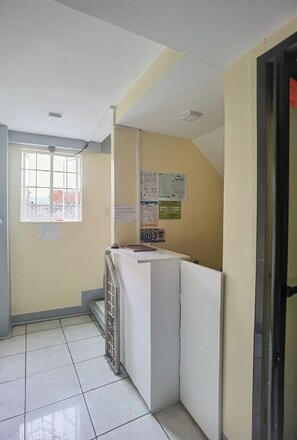 A narrow hallway with a window, a bulletin board, and a door. - Rivoli Hotel (San Pablo)