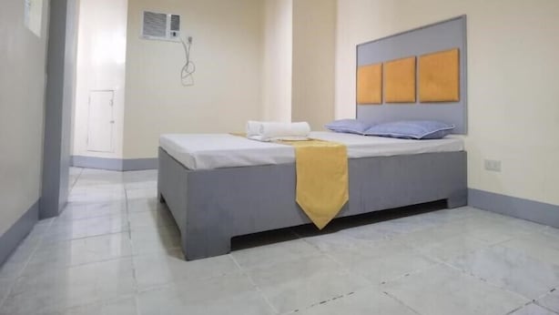 A bedroom with a bed, a bedside table, and a wall-mounted air conditioning unit. - Rivoli Hotel (San Pablo)