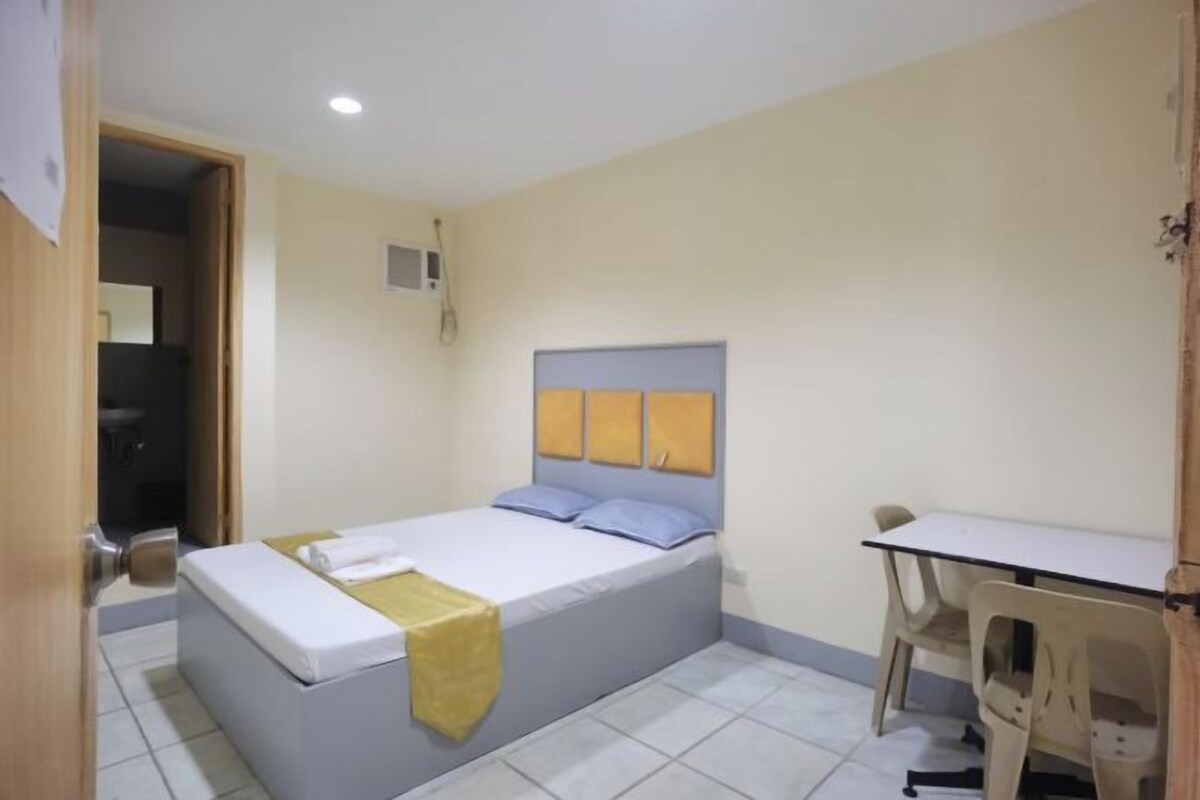 A bedroom with a bed, a desk, and a chair.