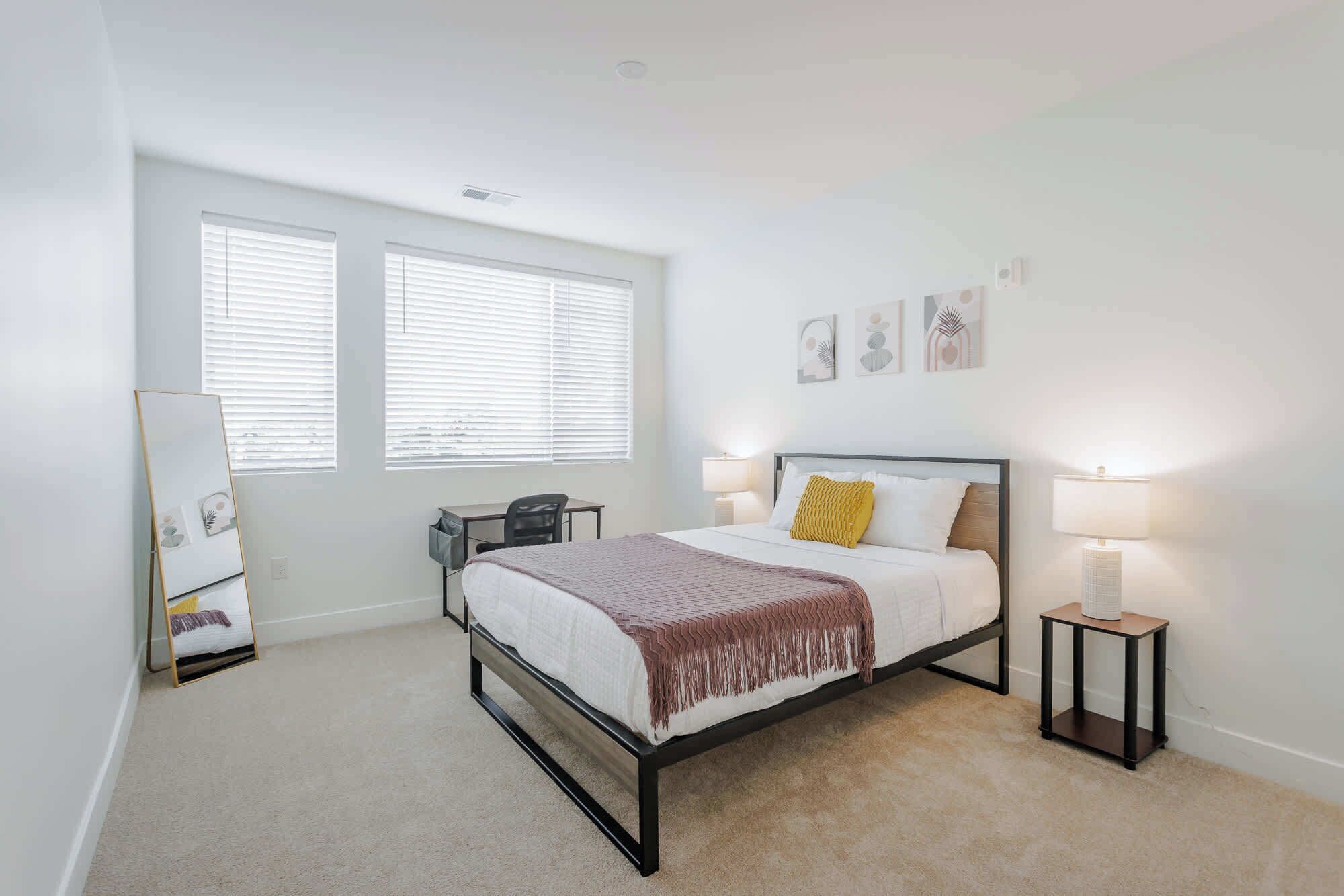 A bedroom with a bed, bedside tables, a desk, and a chair.