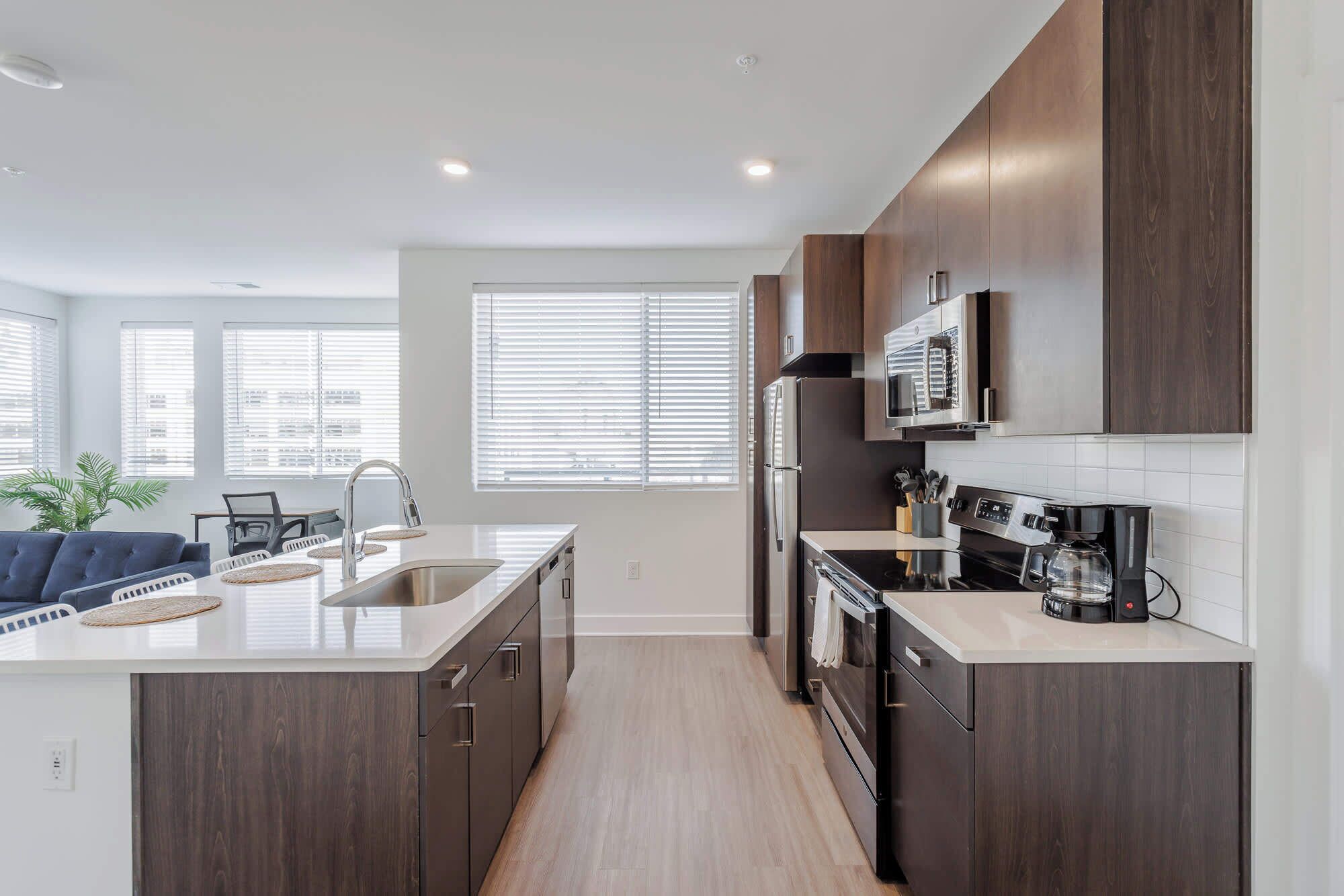 Una cocina moderna con alacenas de madera oscura, electrodomésticos de acero inoxidable y una isla grande con pileta.