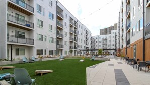 En innergård med en gräsyta, utomhusmöbler och moderna bostadshus.