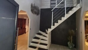 A modern staircase with a metal railing, a wooden floor, and a unique ceiling light fixture.