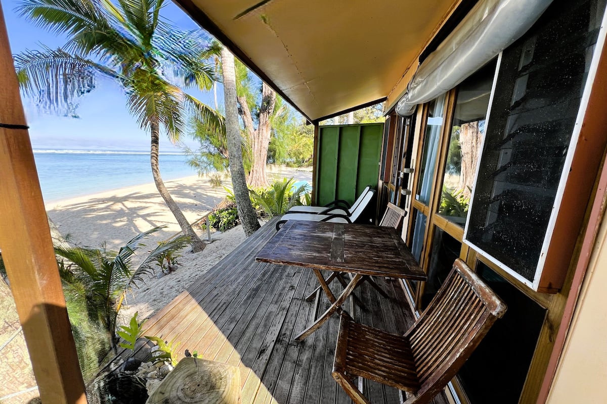 A wooden deck with a table and chairs overlooking a beach.