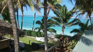 A tropical beach view with palm trees and a clear blue sea. - Te Rito Lagoon Villas (Rarotonga)