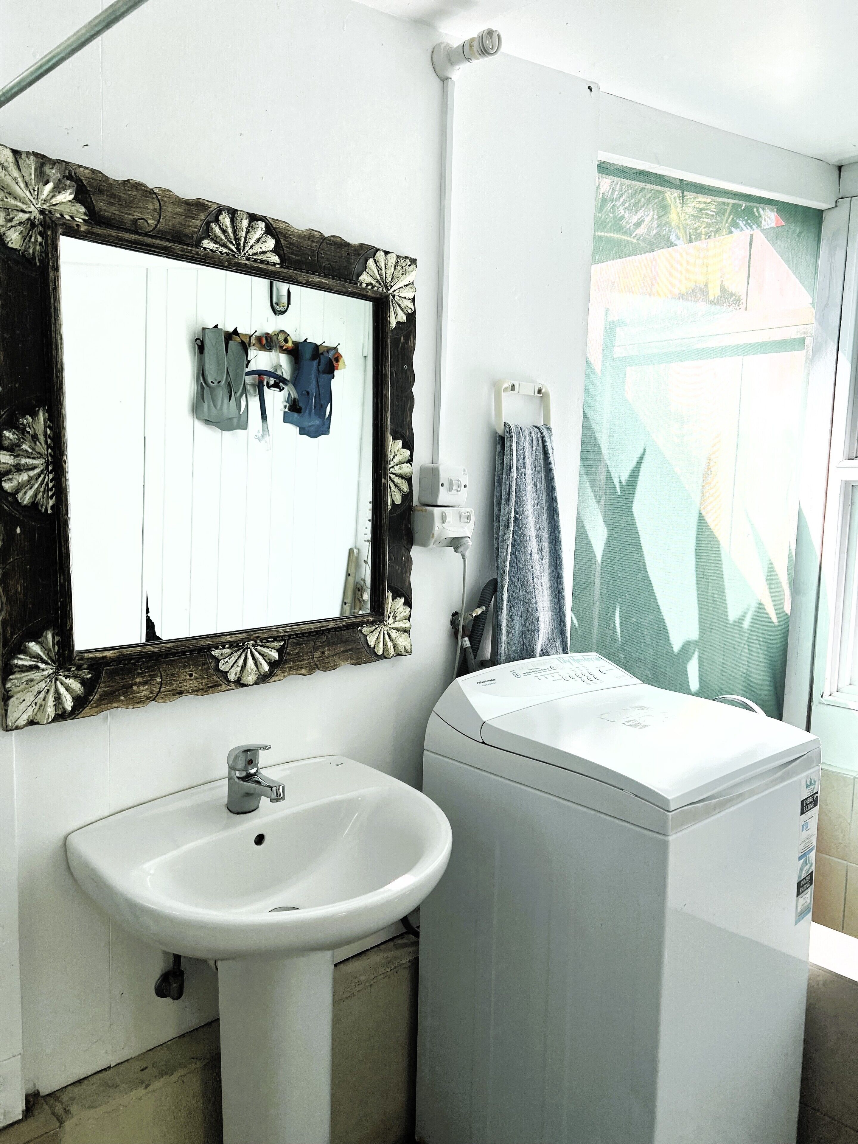 A bathroom with a sink, mirror, and washing machine.