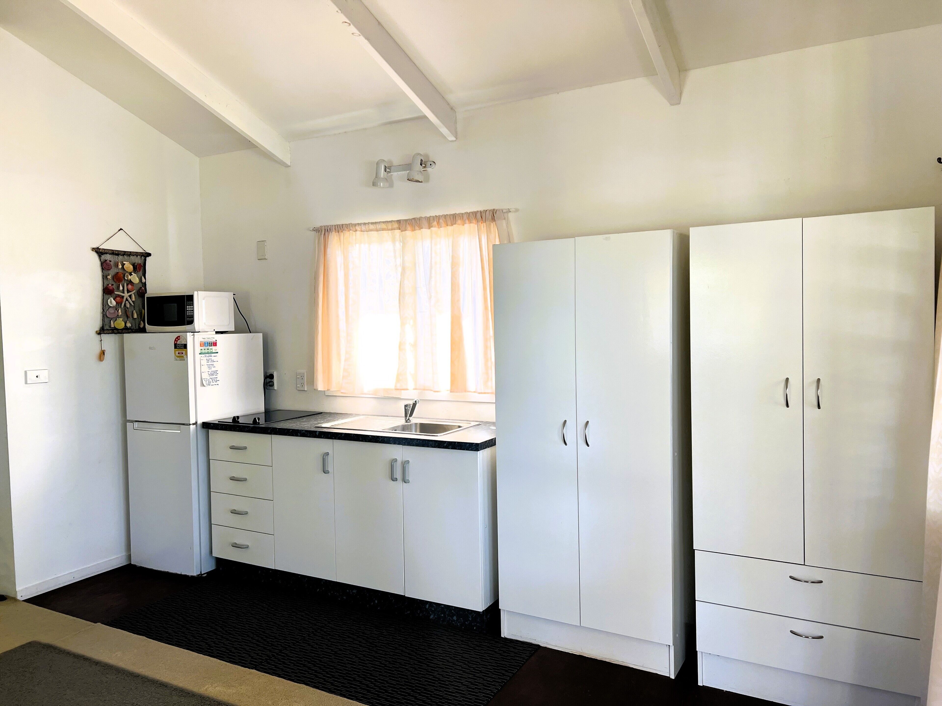 A compact kitchen with white cabinets, a microwave, and a sink.