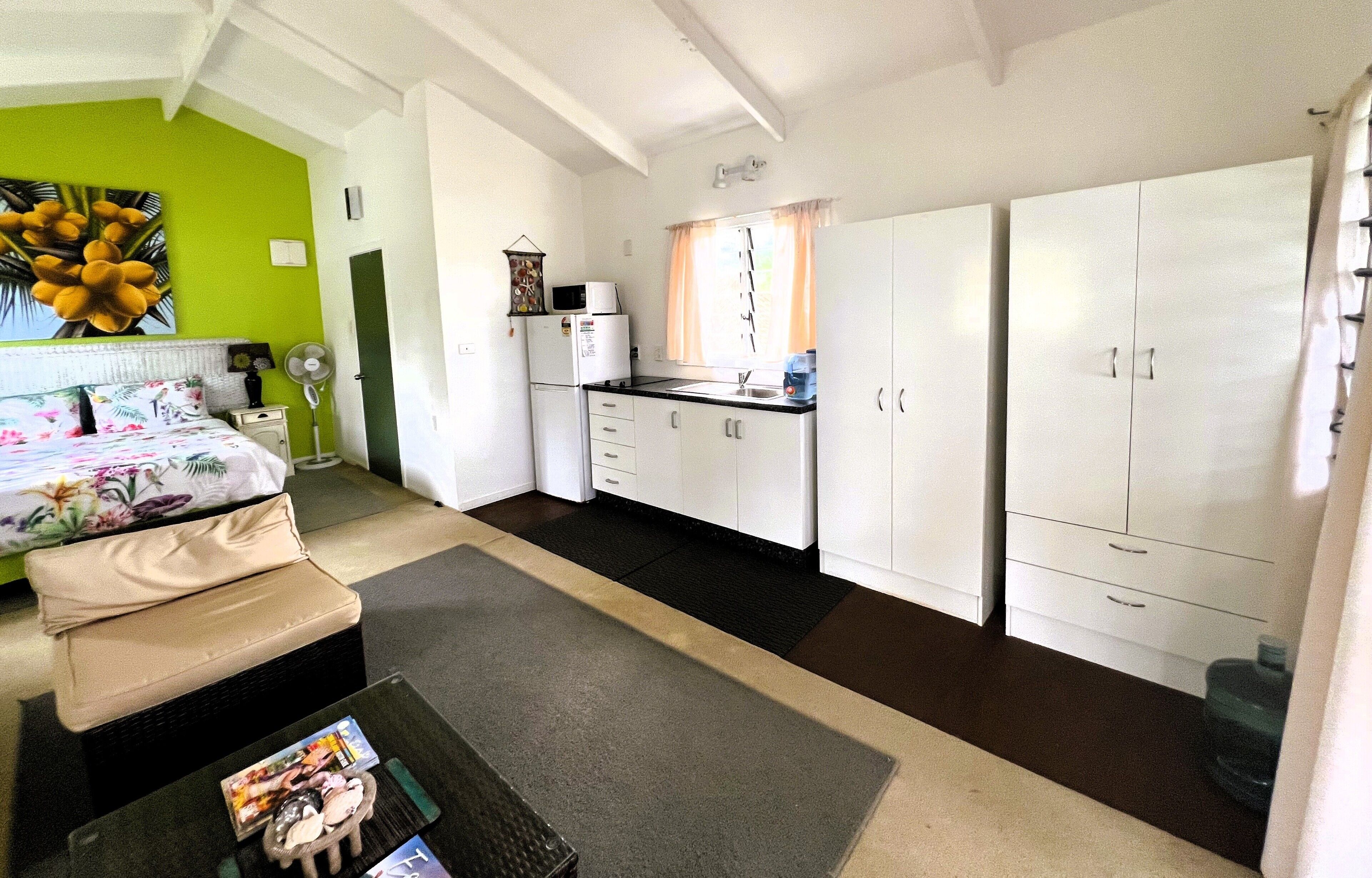 Une chambre de taille réduite comprenant un lit, une kitchenette et un petit coin salon.