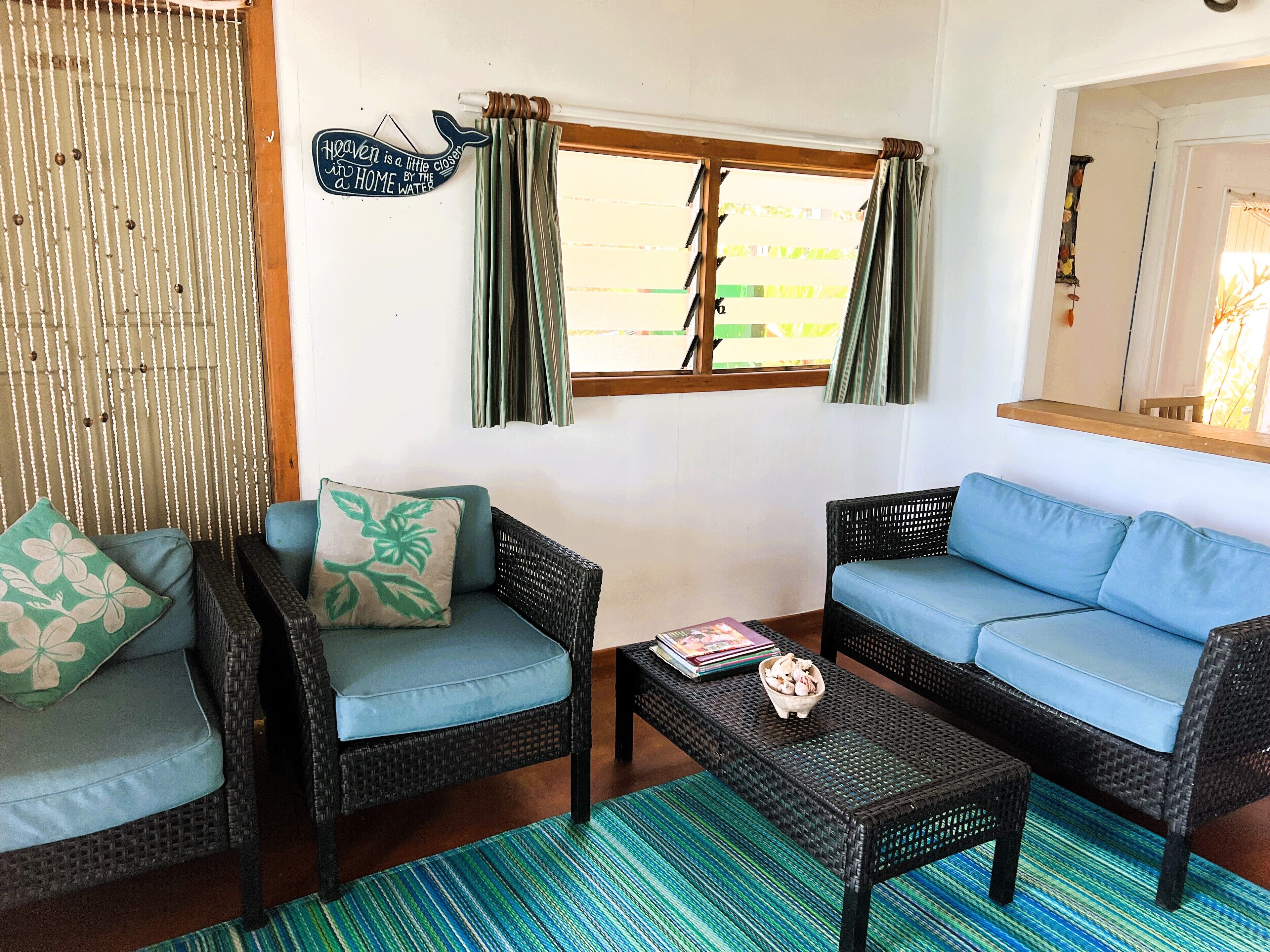A cozy living room with wicker furniture, a blue sofa, and a patterned rug.