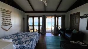 A room with a bed, a sofa, a ceiling fan, and a view of the ocean. - Te Rito Lagoon Villas (Rarotonga)