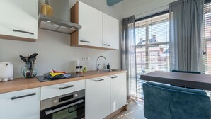 A modern kitchen with white cabinets, a wooden countertop, and a built-in oven. - Cozy apartment in the heart of Sneek (Friesland)