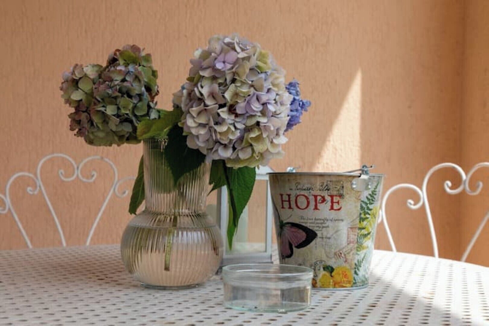 A table with two vases of flowers and a tin labeled "HOPE".