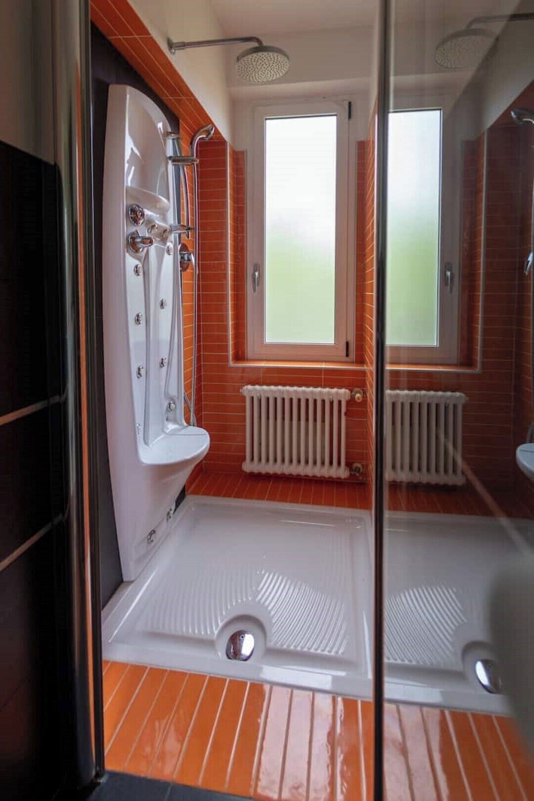 Ein modernes Badezimmer mit Duschkabine aus Glas, einer weißen Badewanne und einem Fenster für natürliches Licht.