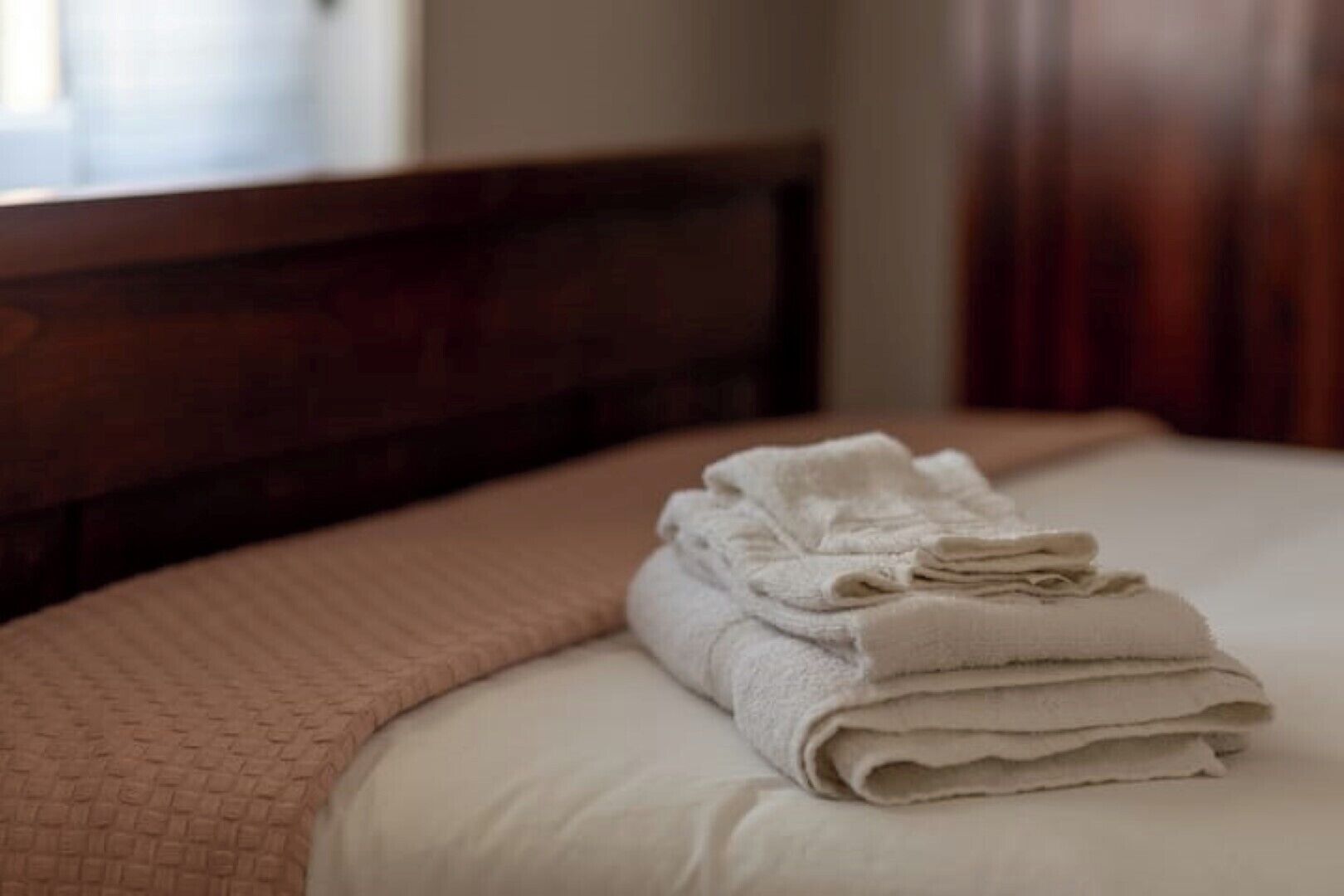 A neatly made bed with a folded white towel on top.