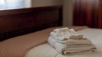 A neatly made bed with a folded white towel on top.