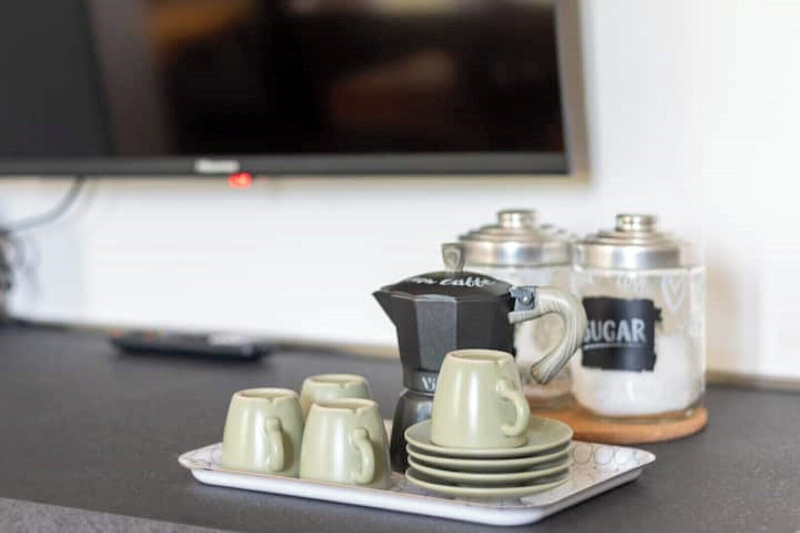 Un ensemble pour préparer le café comprenant une cafetière, un récipient à sucre et quatre tasses, le tout disposé sur un plateau.