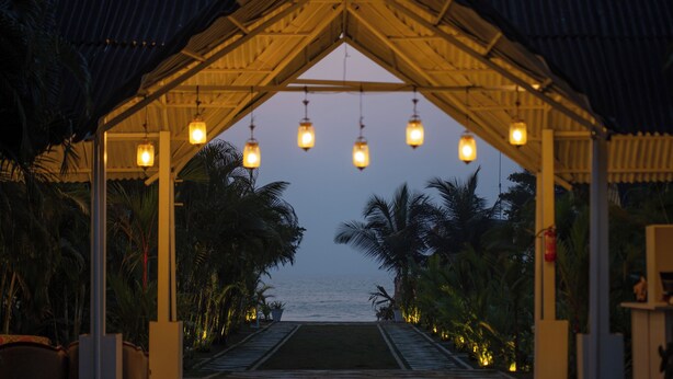 Uma passarela coberta com luminárias penduradas, levando à praia.