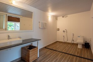 A bathroom with a large mirror, a sink, a toilet, and a shower area. - Royal Agonda (Canacona)