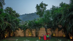 Um jardim com palmeiras, área de recreação e vista para uma colina.