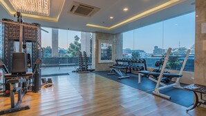 A spacious gym with various exercise equipment, large windows offering a city view, and a modern chandelier. - City Garden Tower by Pattaya Holiday (Pattaya)