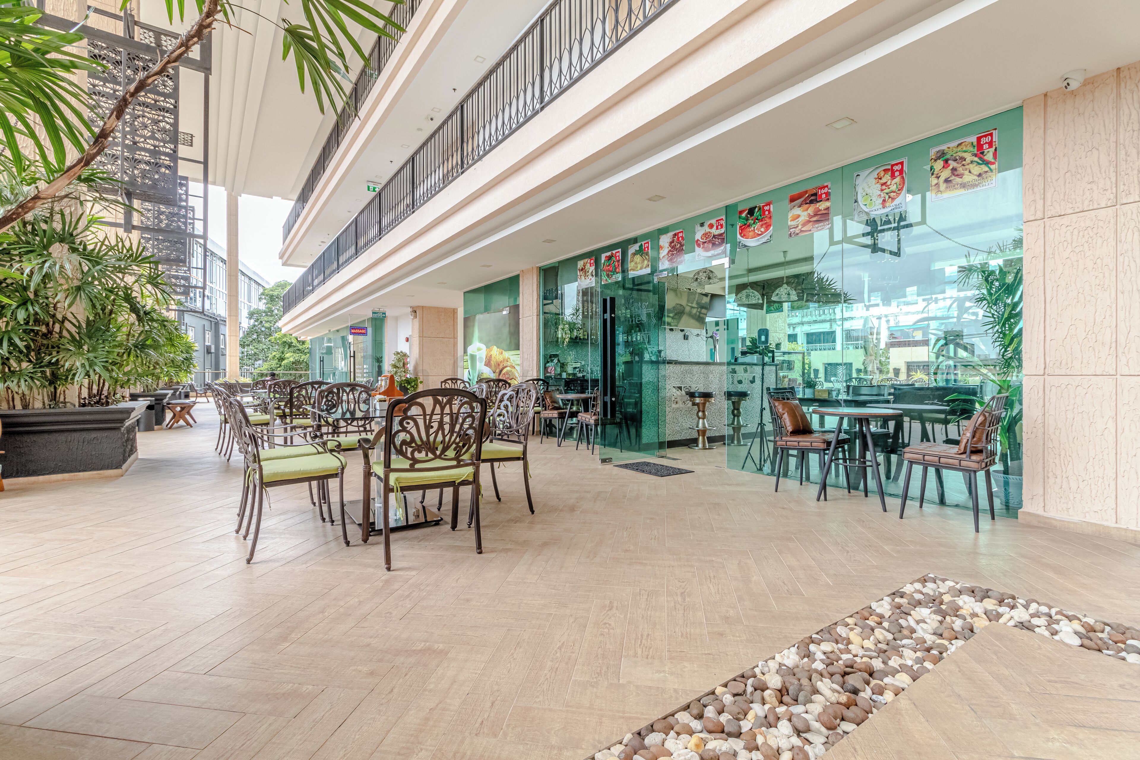 A spacious indoor area with multiple dining tables and chairs, a balcony with a railing, and potted plants.