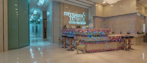 A hotel lobby with a reception desk decorated with festive lights and reindeer statues.