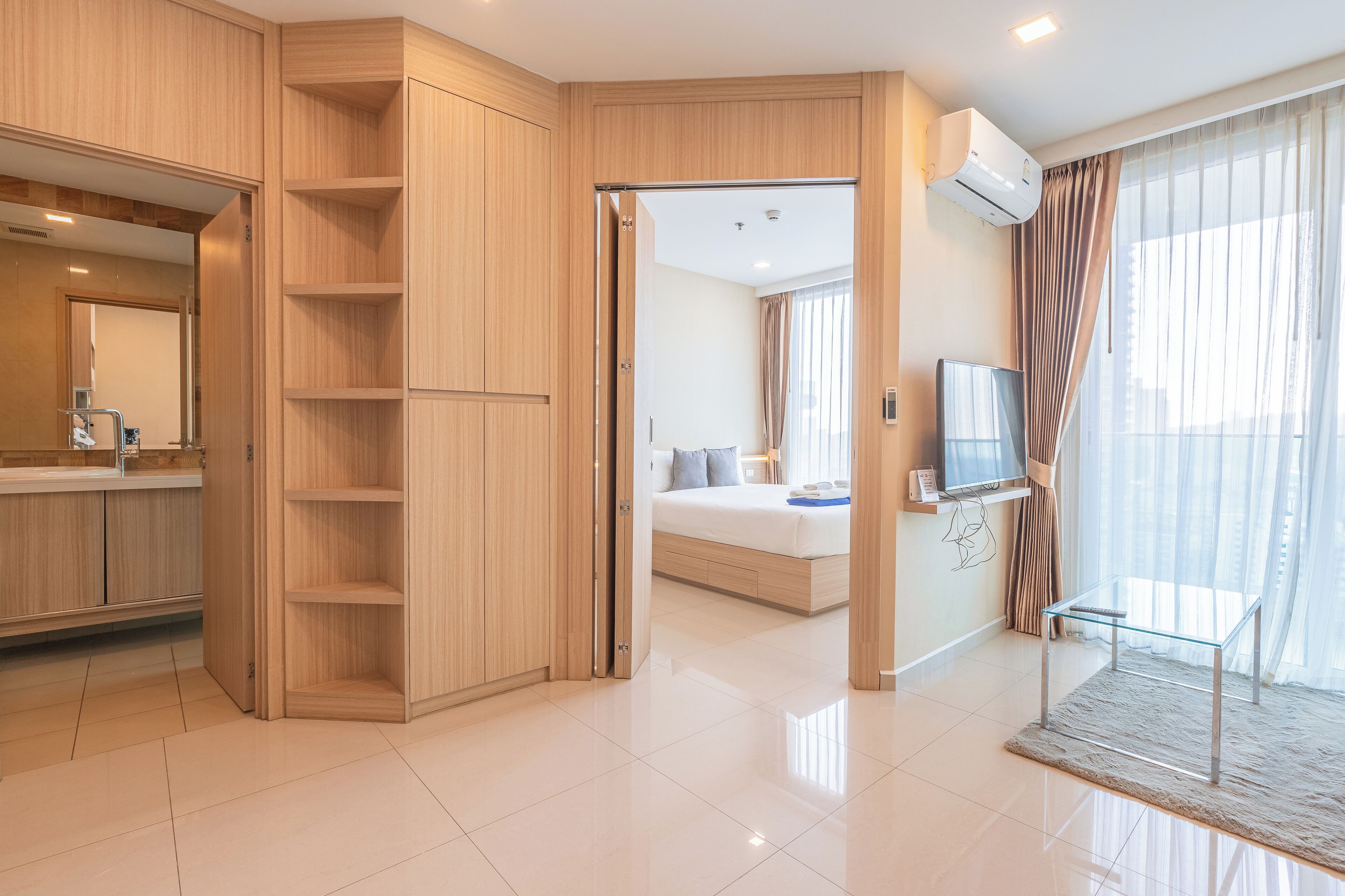 A modern hotel room with a large bed, a TV, and a bathroom with a mirror and sink.