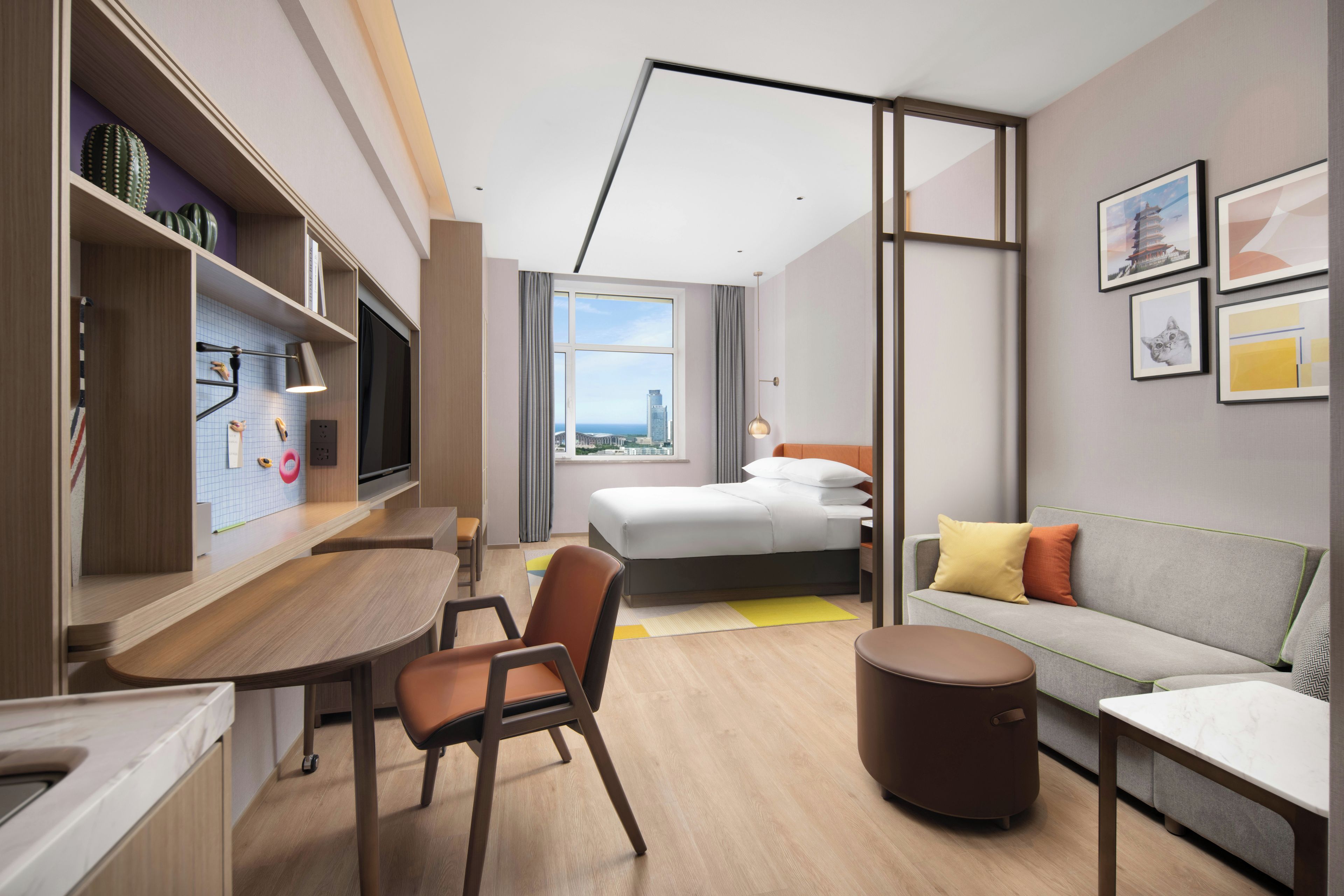 A modern hotel room with a bed, sofa, desk, and chair.