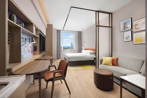 Una habitación de hotel moderna con cama, sofá, escritorio y silla.