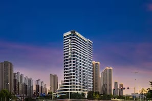Hotel alt, amb nombrosos pisos i un disseny modern, envoltat d'altres edificis.