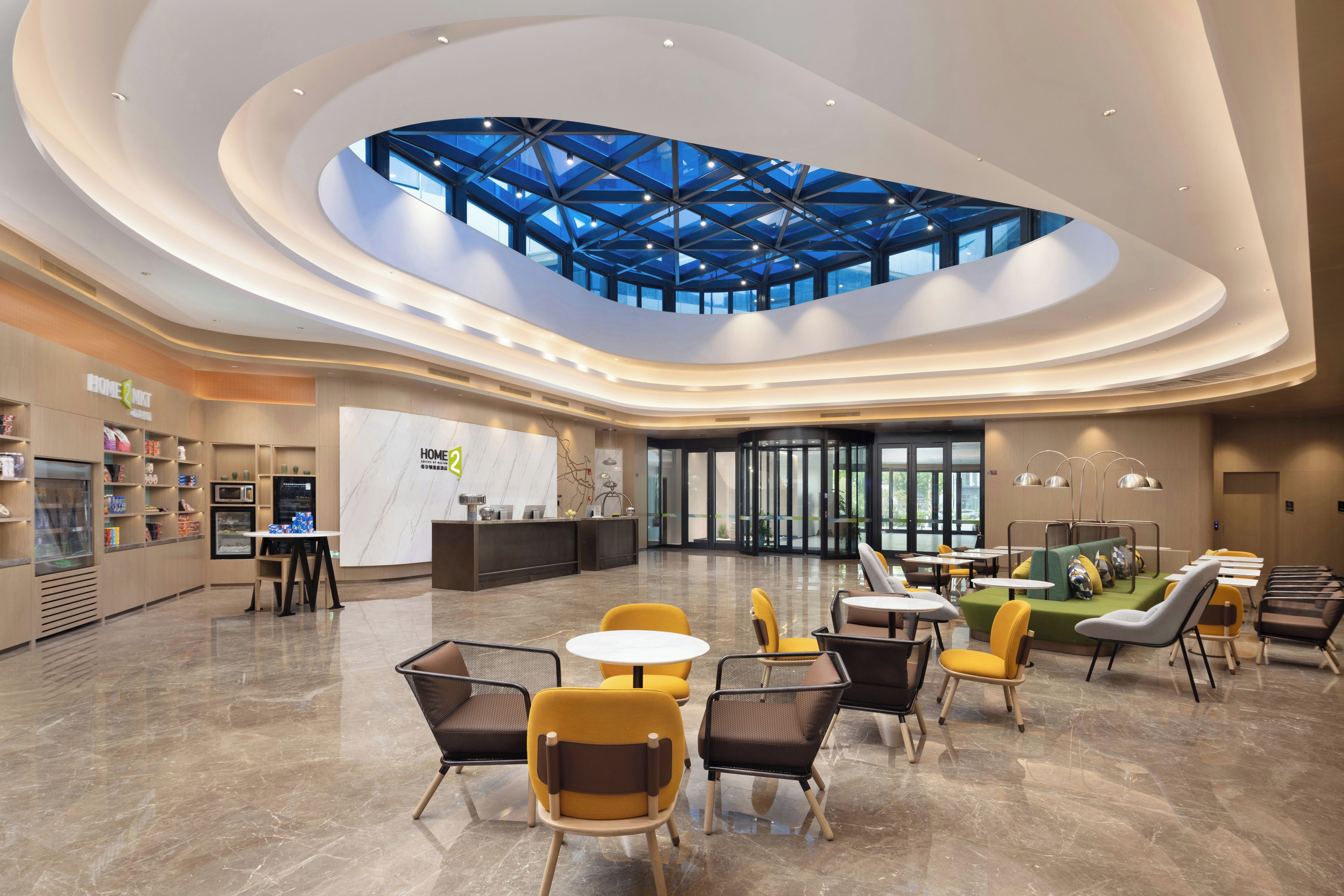 A spacious lobby with a central atrium, a reception desk, and seating areas.