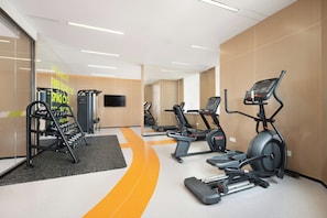 Une salle de sport moderne équipée de tapis de course, de vélos elliptiques et de matériel de musculation.