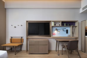 Une chambre moderne équipée d’un téléviseur à écran plat, d’un bureau, d’une chaise, d’un banc et d’une petite armoire.
