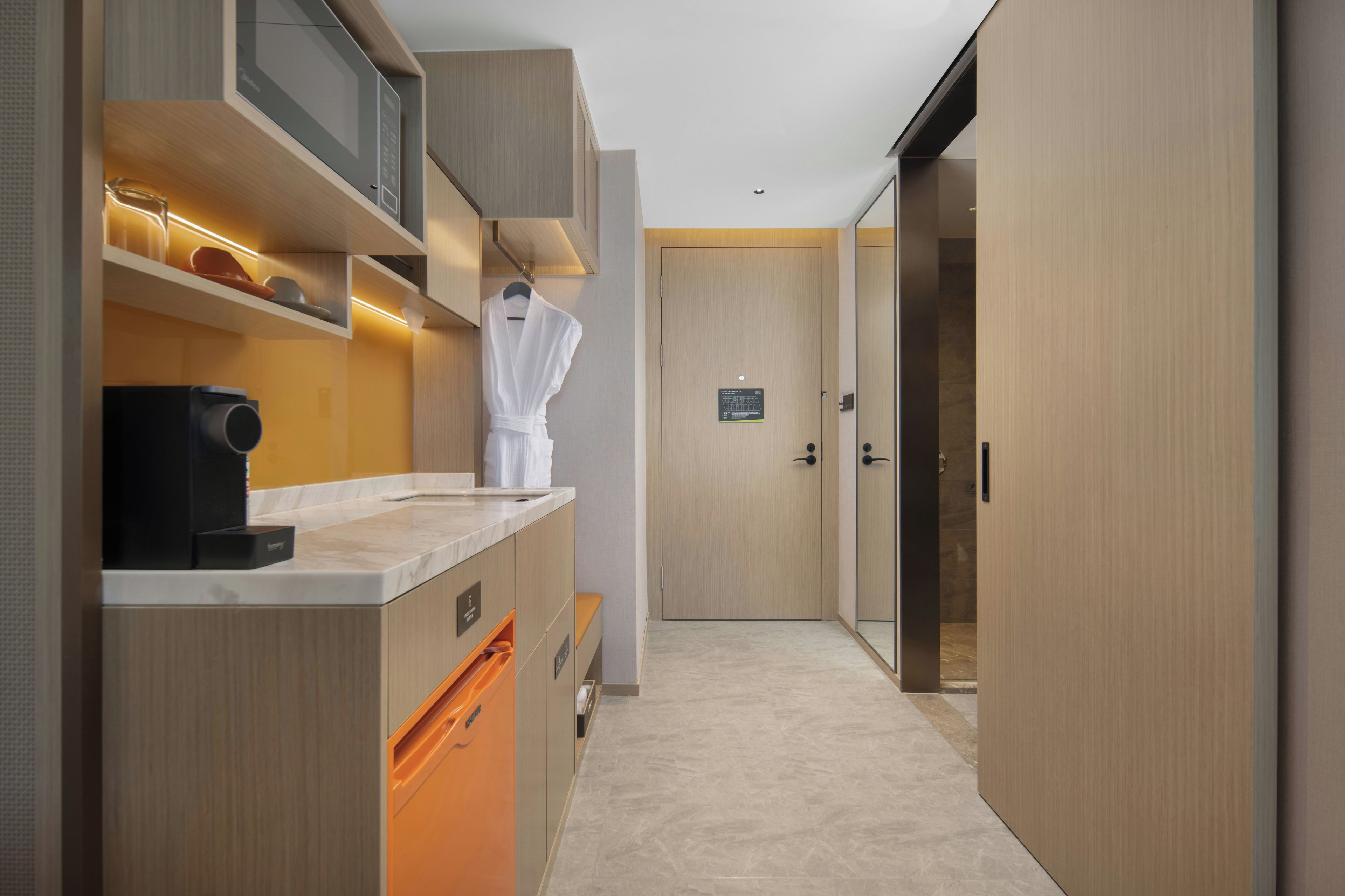 A modern kitchen with a built-in microwave, a coffee machine, and a robe hanging on a rack.